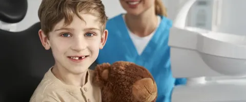 Niño en la oficina dental abrazando un osito de peluche
